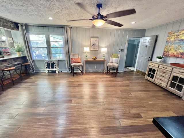 sitting room featuring a textured ceiling, wood-type flooring, and ceiling fan