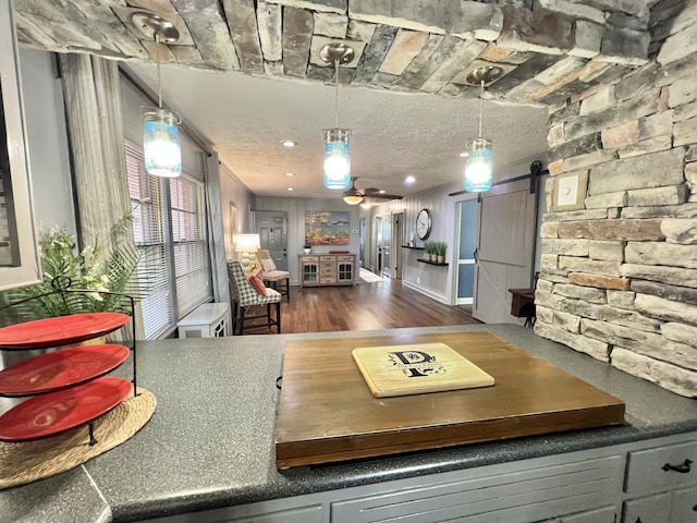 kitchen featuring a textured ceiling, a barn door, pendant lighting, and dark hardwood / wood-style flooring