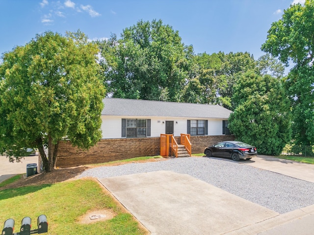 single story home with brick siding, central AC unit, and driveway