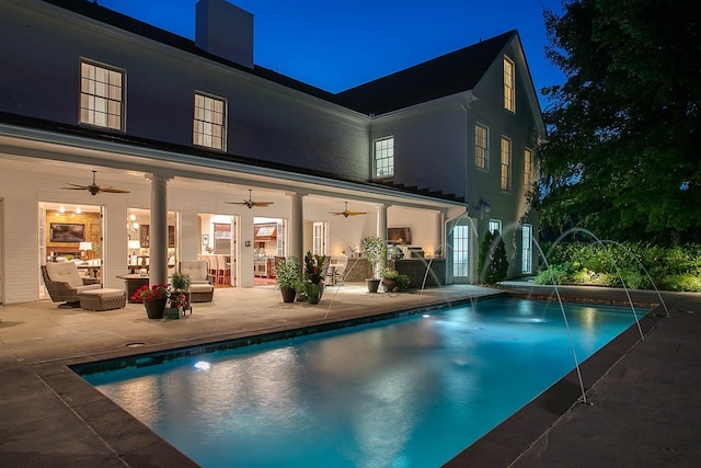 pool at twilight featuring pool water feature, a patio, and ceiling fan