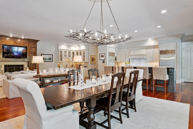 dining room with crown molding, a fireplace, hardwood / wood-style flooring, and an inviting chandelier