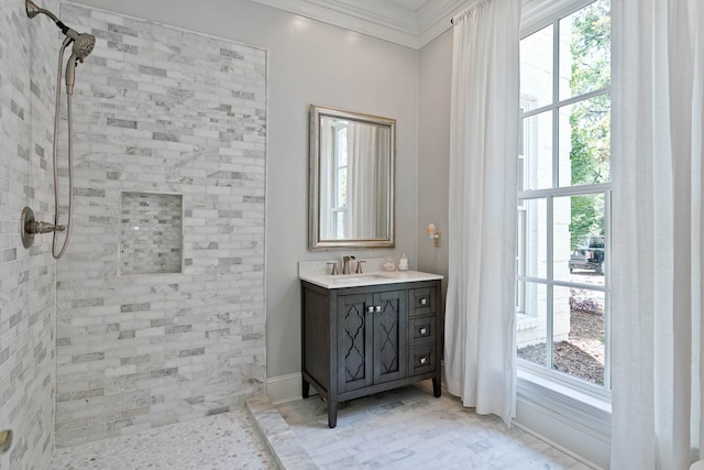 bathroom with tiled shower, vanity, and ornamental molding