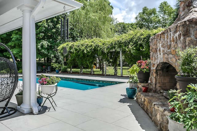 view of pool featuring an outdoor stone fireplace and a patio