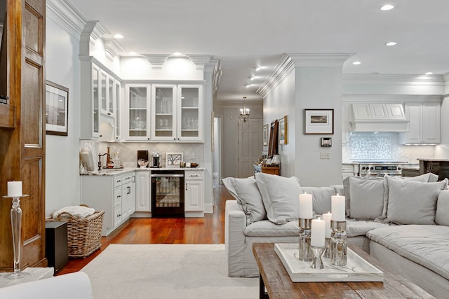 living room with wine cooler, dark hardwood / wood-style flooring, a notable chandelier, crown molding, and sink