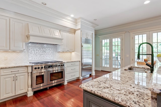 kitchen featuring high end appliances, dark hardwood / wood-style floors, sink, and french doors