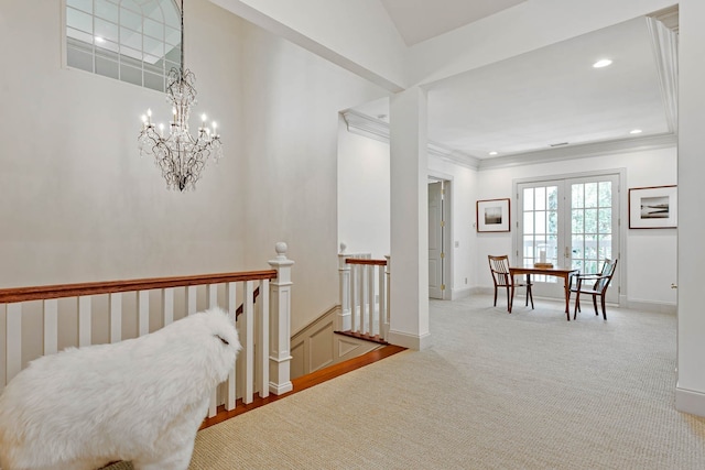 hallway with crown molding, light carpet, a chandelier, and french doors