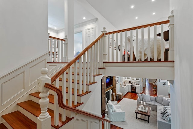 stairs with hardwood / wood-style flooring and crown molding