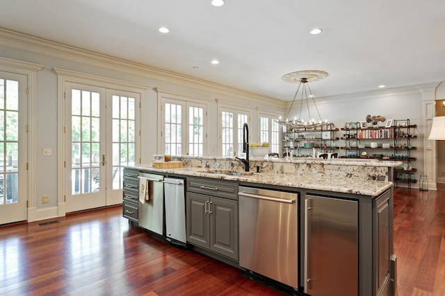 kitchen featuring dark hardwood / wood-style flooring, dishwasher, light stone counters, and a center island with sink