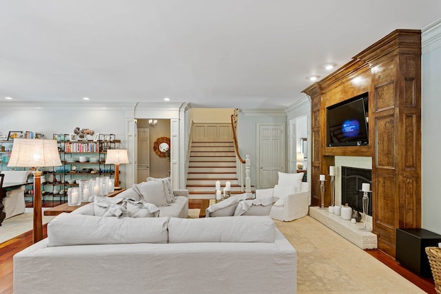 living room with a large fireplace, hardwood / wood-style floors, and ornamental molding