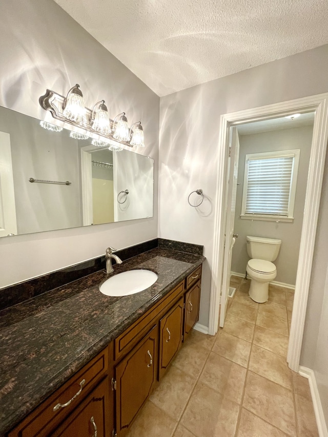 bathroom featuring a textured ceiling, vanity, toilet, and tile patterned floors