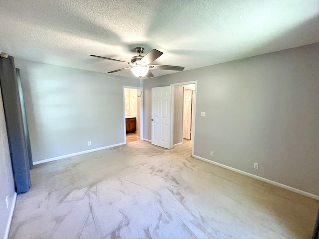 unfurnished bedroom featuring a textured ceiling, light colored carpet, ceiling fan, and ensuite bathroom