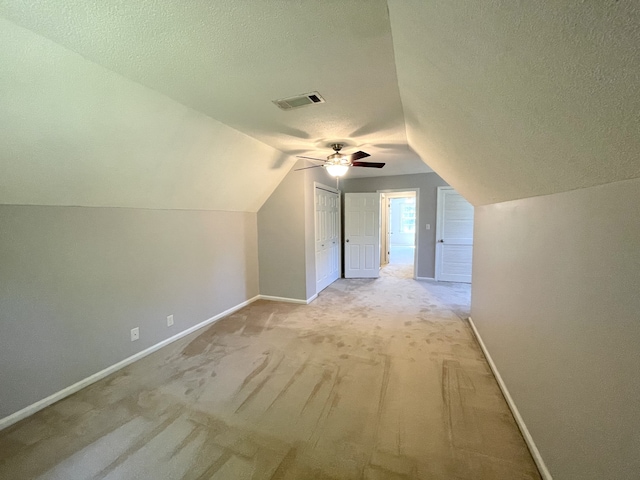 additional living space featuring lofted ceiling, light colored carpet, a textured ceiling, and ceiling fan