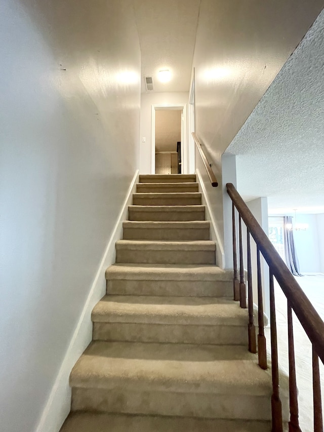 stairway featuring a textured ceiling