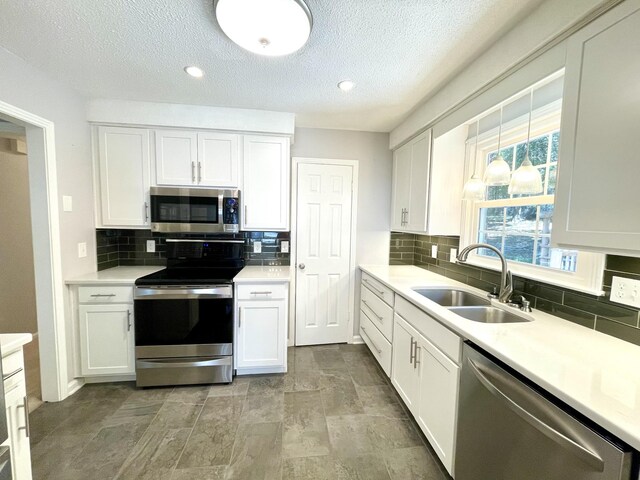 kitchen featuring a textured ceiling, backsplash, stainless steel appliances, sink, and white cabinets