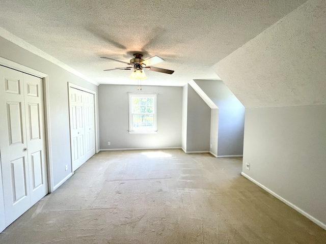 bonus room with ceiling fan, light colored carpet, vaulted ceiling, and a textured ceiling