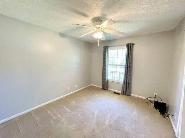 empty room featuring light carpet, a textured ceiling, and ceiling fan