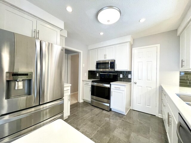 kitchen featuring a textured ceiling, stainless steel appliances, white cabinetry, and tasteful backsplash