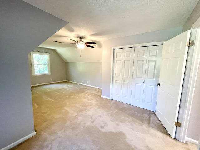 additional living space featuring a textured ceiling, light colored carpet, ceiling fan, and vaulted ceiling