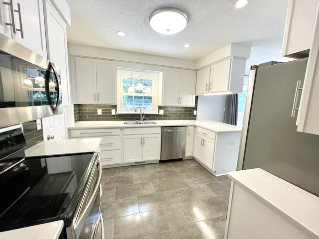 kitchen featuring appliances with stainless steel finishes, white cabinetry, backsplash, and sink