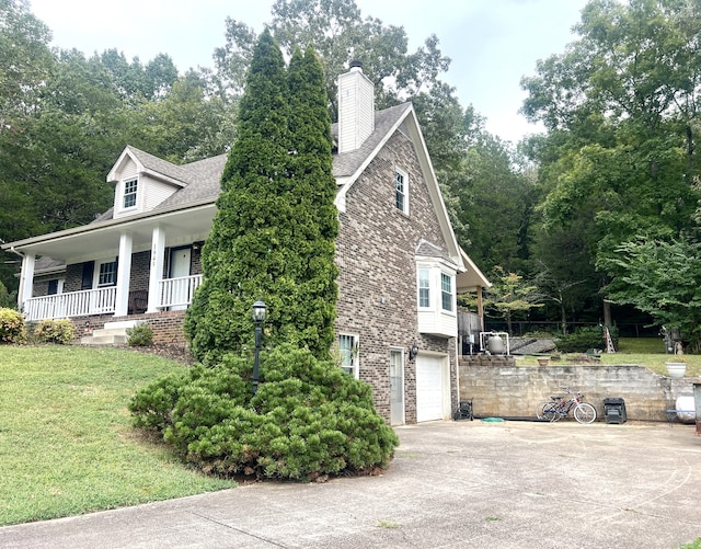 exterior space featuring a garage, a porch, and a lawn