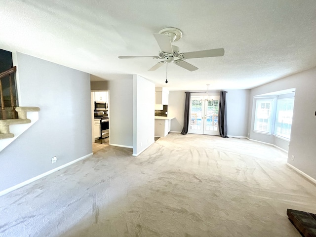 unfurnished living room with ceiling fan, light colored carpet, and a textured ceiling