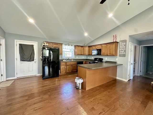 kitchen featuring black appliances, vaulted ceiling, kitchen peninsula, and dark hardwood / wood-style flooring