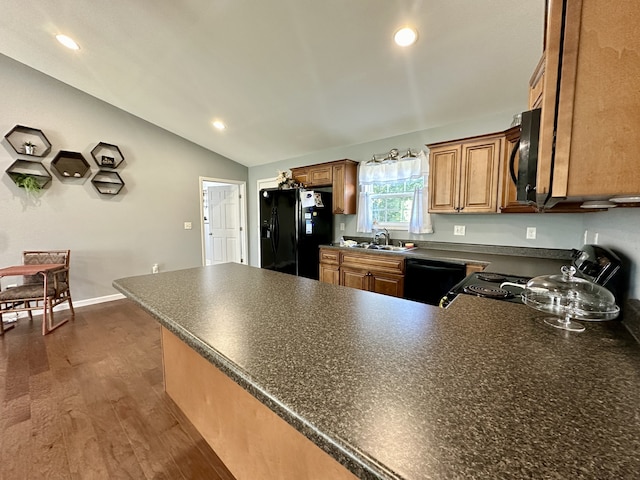 kitchen featuring vaulted ceiling, dark hardwood / wood-style floors, black appliances, kitchen peninsula, and sink