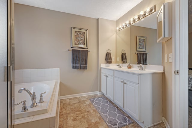 bathroom featuring vanity, tiled bath, and a textured ceiling