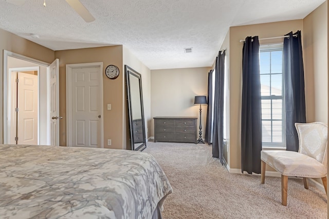 bedroom featuring light carpet, ceiling fan, and a textured ceiling