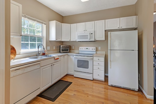 kitchen with white cabinetry, sink, and white appliances