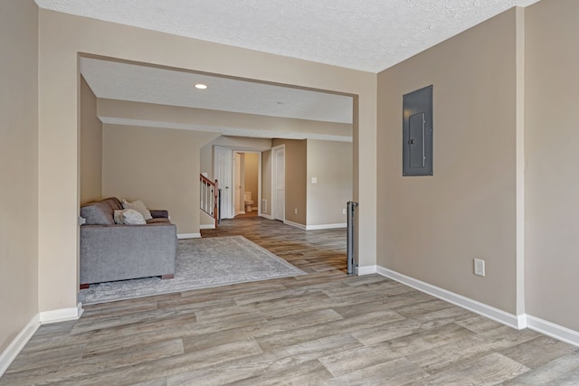 unfurnished room with electric panel, a textured ceiling, and light wood-type flooring