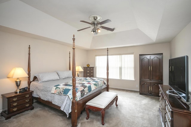 carpeted bedroom with a raised ceiling and ceiling fan