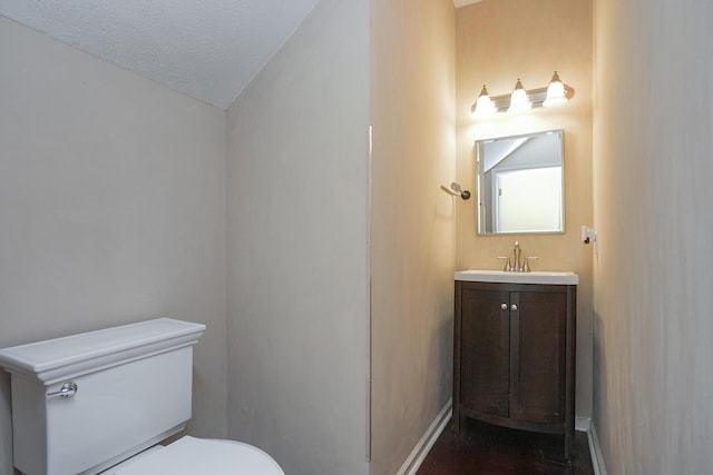 bathroom with toilet, lofted ceiling, wood-type flooring, vanity, and a textured ceiling