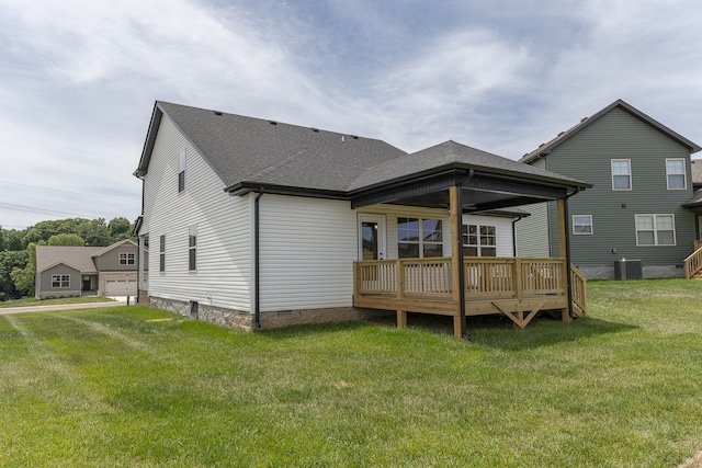 rear view of house featuring a yard, a garage, a deck, and central air condition unit