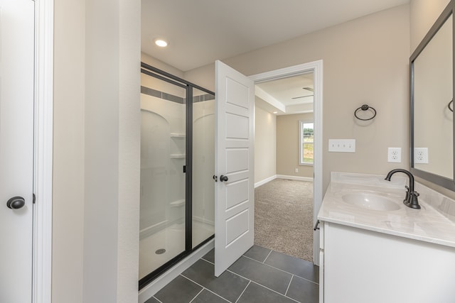 bathroom with a shower with door, vanity, and tile patterned flooring