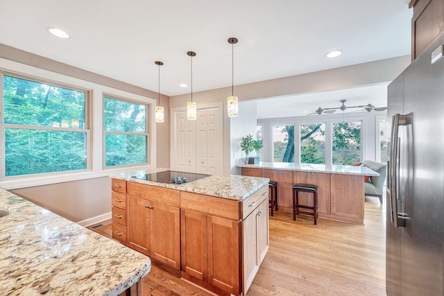 5053 Villa Crest Dr, Nashville, TN 37220 - kitchen featuring freestanding refrigerator, black electric cooktop, a center island, light wood finished floors, and light stone countertops