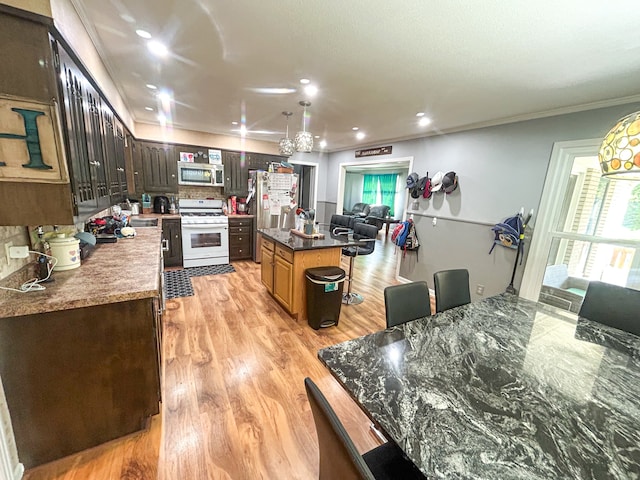 kitchen featuring a center island, light hardwood / wood-style flooring, appliances with stainless steel finishes, decorative backsplash, and ornamental molding