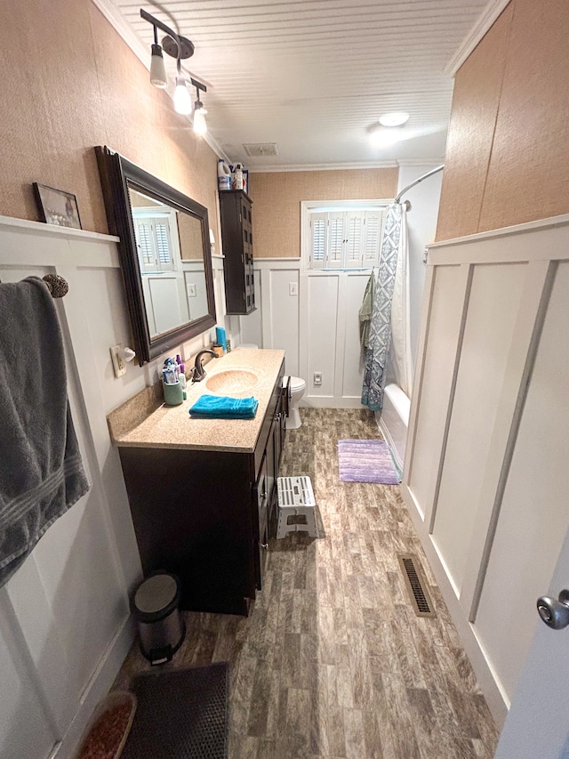 full bathroom featuring hardwood / wood-style flooring, crown molding, shower / bath combo, toilet, and vanity