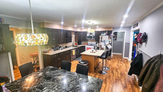 kitchen with dark brown cabinetry, sink, a center island with sink, appliances with stainless steel finishes, and a kitchen breakfast bar