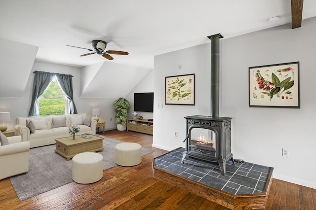 living room with lofted ceiling with beams, hardwood / wood-style floors, ceiling fan, and a wood stove