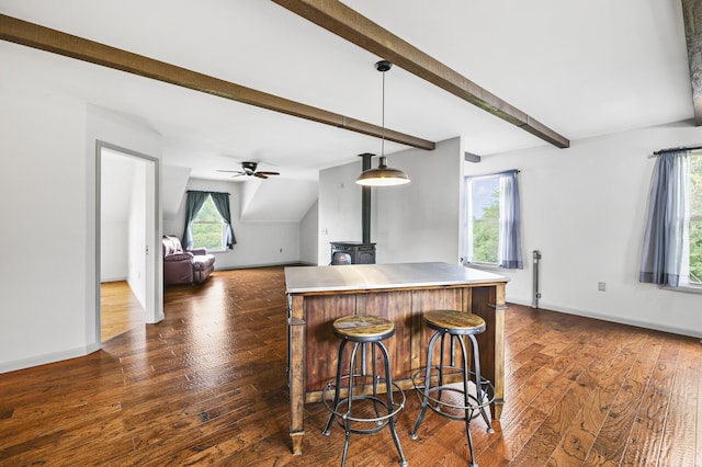 kitchen featuring dark hardwood / wood-style floors, a kitchen breakfast bar, pendant lighting, stainless steel counters, and ceiling fan