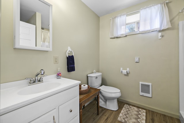 bathroom with toilet, hardwood / wood-style flooring, heating unit, and vanity