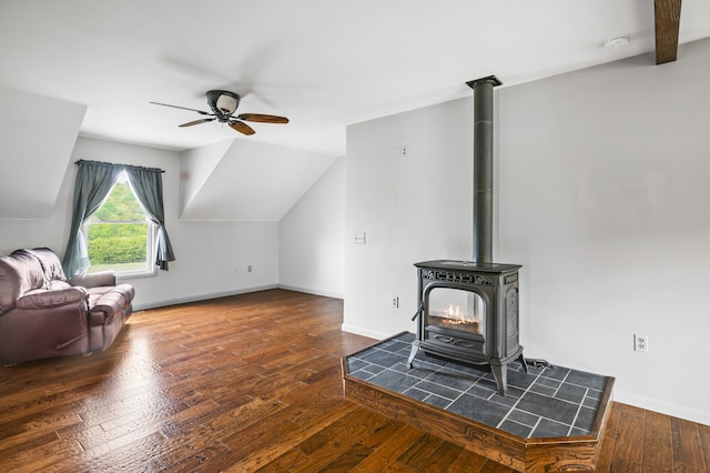 living room featuring a wood stove, dark wood-type flooring, ceiling fan, and beam ceiling