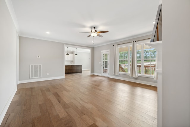 unfurnished living room featuring ceiling fan, ornamental molding, and wood-type flooring