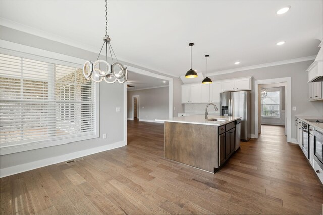 kitchen with hanging light fixtures, hardwood / wood-style flooring, a center island with sink, and white cabinetry