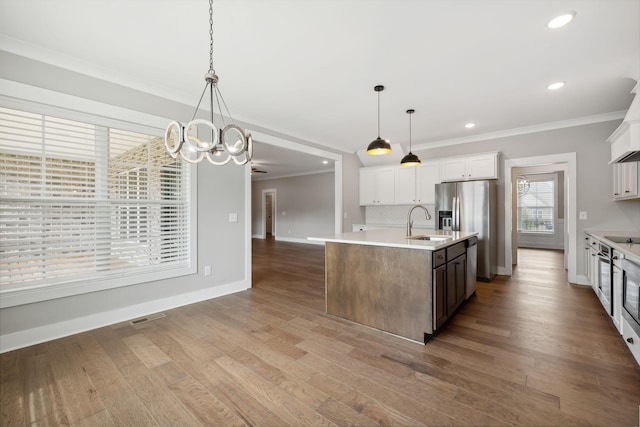 kitchen featuring light countertops, a center island with sink, visible vents, and a sink