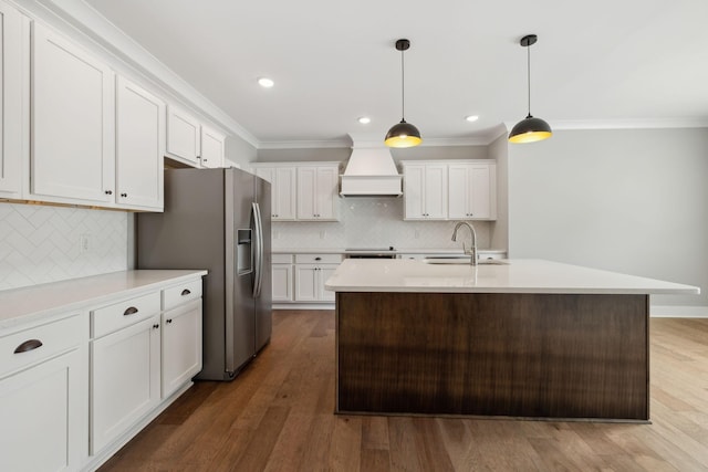 kitchen with crown molding, light countertops, wood finished floors, custom exhaust hood, and a sink