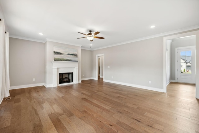 unfurnished living room featuring light wood-style flooring, a fireplace, crown molding, and baseboards