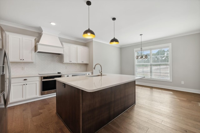 kitchen featuring premium range hood, dark wood finished floors, light countertops, stainless steel appliances, and a sink