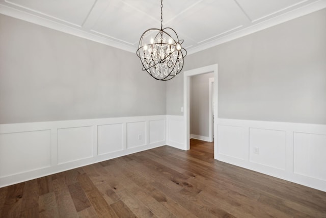 unfurnished dining area featuring a chandelier, a wainscoted wall, wood finished floors, and a decorative wall